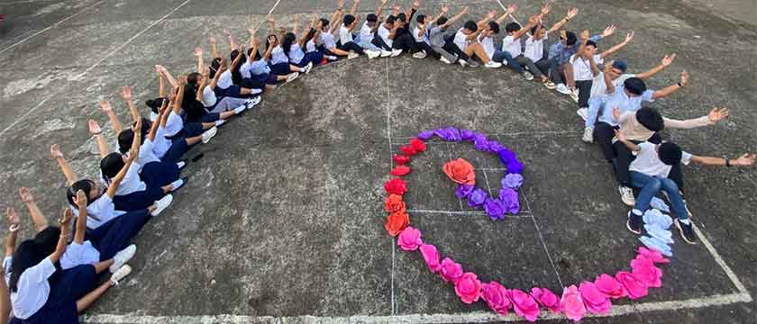 A Golden Spiral formed on the schoolyard floor by children sitting on a row, and continued toward the center with flowers in a variety of warm colors